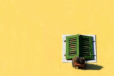 a green window on a yellow wall.の写真素材