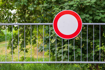 No-drive road sign attached to a barrier surrounded by green countryside vegetation.の写真素材