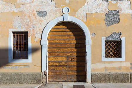 Facade of an old and ancient house with two windows and door, driveway, uninhabited and abandoned in the historic center of the city.の写真素材