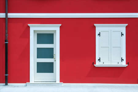 House facade with red wall with door, window and white decorations.の写真素材