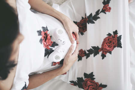Top view pregnant woman sitting hands on her belly, and baby shoes on her bellyの写真素材