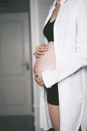 standing pregnant woman hands on her bellyの写真素材