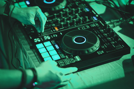 DJ hands on stage mixing, disc jockey and mix tracks on sound mixer controller, playing music for...
