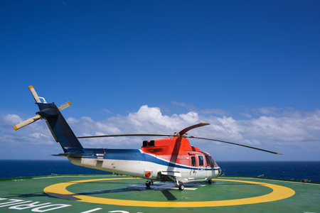 Helicopter shut down engine on oil rig helipad with blue sky