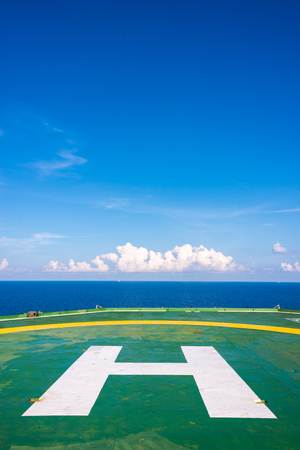 Empty oil rig helipad with few cloud and blue sky, H sign at center in vertical in Gulf of Thailandの写真素材