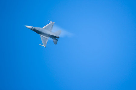 fighter aircraft's vapor condensation on its wing with clear blue sky