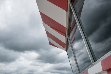 Aerodrome control tower painted chekered red and white with cloudy skyの写真素材
