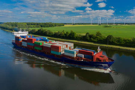 Container ship on the Kiel Canal and windmill on the background.の写真素材