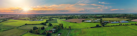 Sunny panorama of rural idyll with agricultural factory, fields, and wind turbines on the background in the countryside. Magical country landscape in autumn.の写真素材
