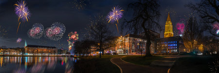 New Year celebrations on New Years Eve with fireworks. Festive view of Kiel skyline, Kiel Opera House, the town Hall by Kleiner Kiel at night with fireworks.のeditorial素材