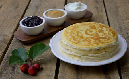 Russian pancakes crepes with raspberry jam, apple sauce and sour cream on rustic wooden background. Stack of russian pancake blini on a wooden background.Delicious homemade crÃªpes or pancakes.の写真素材