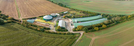 Panorama aerial view of countryside with biogas plant. Aerial view of fields with agricultural factory in the countryside. Preparation of forage corn for storage after harvesting.の写真素材