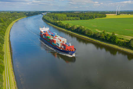 Container ships on the Kiel Canal and windmill on the background.の写真素材