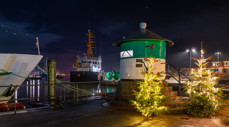 Green pier light and cristmas trees in the fishing port of BÃ¼sum on the German North Sea coast, Dithmarschen, Schleswig-Holstein, Germany. Christmas romantic atmosphere in the BÃ¼sum at night.の写真素材