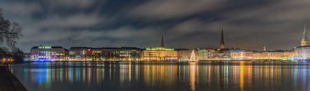 Advent, Christmas in Hamburg. Panorama view of the decorated city center from Alster Lake, view to Hamburg Rathaus and a Christmas tree installed in the center of the lake.Atmosphere before the New Yearの写真素材