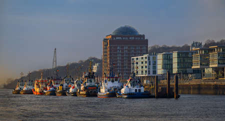 Tug boats moored at a pier. Tug bridge with moored tug boats. Tugboats moored at bollards by the pier New tugboat bridge in NeumÃ¼hlen Hamburg. Tug boats docked on the banks of the Elbe river.の写真素材