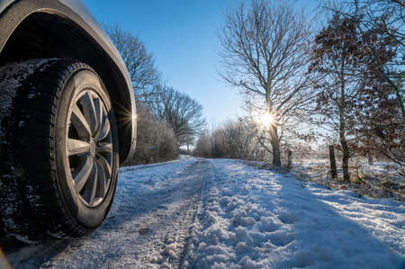 Car tires in winter on the road covered with snow. Winter road and wheel of a car with snow. Winter tire. Car on snow road. Tires on snowyway detail.の写真素材