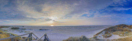 Bathing and beach vacation on the North Sea. Stunning view from Wadden Sea coastline. Stairs leading...