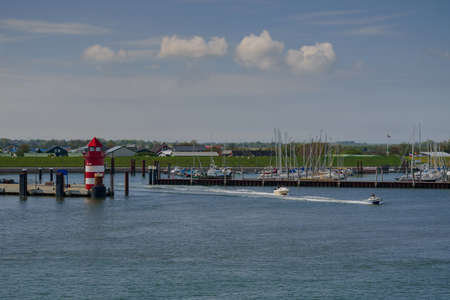 peed boats on the sea, getting out from the port Wyk auf FÃ¶hr. Motorboats leaving marina Wyk auf Foehr. Coastal landscape with marina at Wyk auf Foehr. Red pier light in harbor of Wyk auf FÃ¶hr.の写真素材