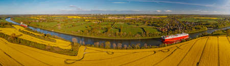 Panorama view of countryside with biogas plant. Yellow flowering rapeseed field with agricultural factory in the countryside.Renewable energy from biomass.の写真素材
