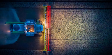 Working combine harvester at night with lights illuminating the field. Combine harvesters are harvesting wheat at night.の写真素材
