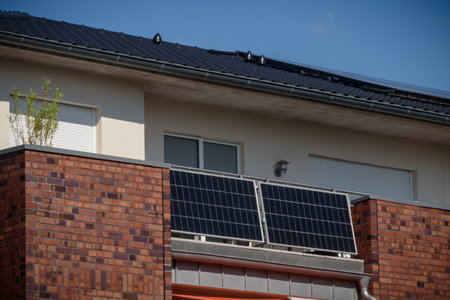 Modern residential building with solar panels on a balcony railing and on roof. Solar panels on balcony, approach of integrating renewable energy sources into urban design to reduceの写真素材
