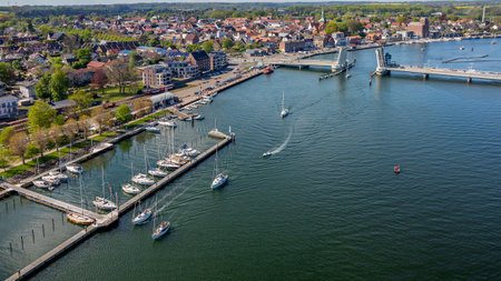 Aerial view of Kappeln on inlet Schlei in northern Germany with open bascule bridge, marina, sailboats and historic town. Open bascule bridge in Kappeln with sailboats passed throughの写真素材