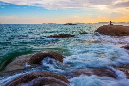 people in view of a rocky coast in sunsetの写真素材