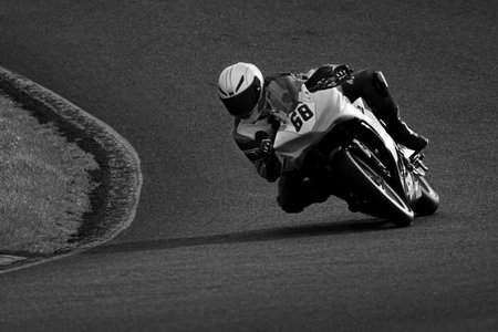 A monochrome shot of a racing motorbike as it circuits a track.