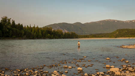 Terrace, Canada - July 20th 2017: An angler fly fishing on the Skeena River at sunset in summer, Terrace, British Columbia, Canadaのeditorial素材