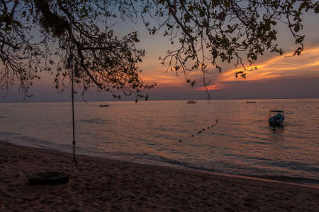 Rope swing and boat at sunset on Melina Beach, Tiomen Islandの写真素材