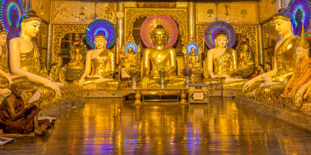 Yangon, Myanmar - December 18th 2017: A burmese buddhist monk praying inside a room with Buddhas at the Shwedagon Pagodaのeditorial素材