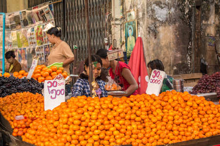 Yangon, Myanmar - December 18th 2017: A Burmese women selling oranges in a street market in Yangon, Myanmar. Translation "900 Burmese Kyat"のeditorial素材