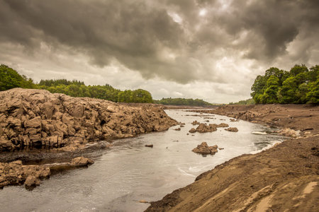 The Water of Ken river in the drained or dewatered Earlstoun Dam and Loch / reservoir , on the...