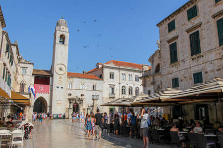 Dubrovnik, Croatia - July 15th 2018: The Stradun main street, cafe and clock tower in Dubrovnik's old town, with tourists in the summer, Croatiaのeditorial素材