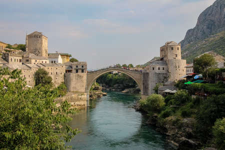 A landscape view of the old town of Mostar, with the old arched bridge over the Neretva River, with Hum Hill in background, Bosnia and Herzegovinaのeditorial素材