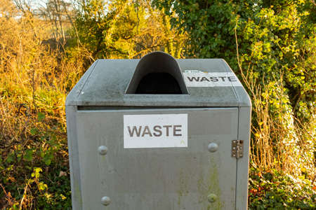 Waste sign on a silver steel trash can or bin in the countryside parkの写真素材