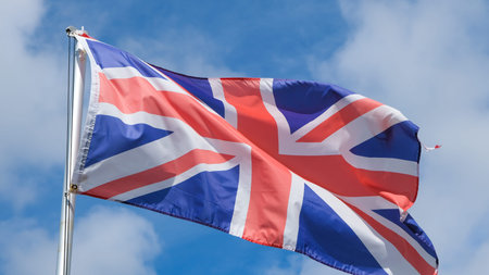 A Union Jack Flag flying from a flag pole in the sky, the national flag of the United Kingdom of...