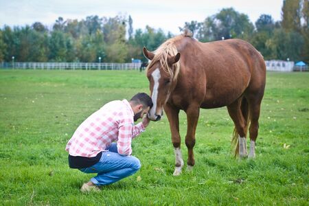 Young handsome guy Cowboy. man is a farmer in his ranch where there are many horses. Rural landscapes, countryside. Stock photosの写真素材