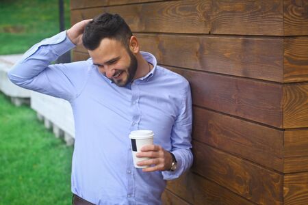 Portrait of a businessman, manager on a wooden wall background. A bearded sexy man in a shirt. Stock photosの写真素材