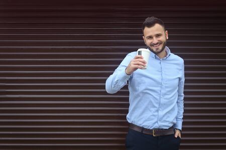 Portrait of a businessman, manager on a striped wall background. Bearded sexy man singing coffee, tea. Stock photosの写真素材
