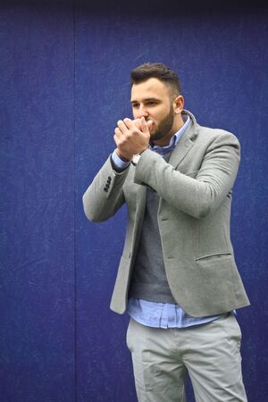Fashionably dressed man against a blue wall. Cold winter, autumn weather. A warming guy. Stock Photo for designの写真素材