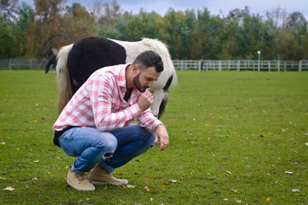 Young handsome guy Cowboy. man is a farmer in his ranch where there are many horses. Rural...