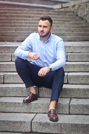 Portrait of a bearded man near the big steps of an old European castle. Businessman thinking over a future project. Fashionable guy with stylish clothes.の写真素材