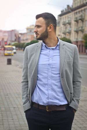 Portrait of a businessman on the street near the road of a European city. A bearded handsome man dressed stylishly. Fashionable guy hipster. Stock photosの写真素材