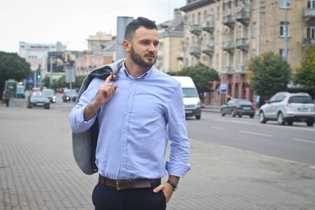 Portrait of a businessman on the street near the road of a European city. A bearded handsome man dressed stylishly. Fashionable guy hipster. Stock photosの写真素材