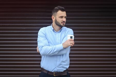 Portrait of a businessman, manager on a striped wall background. Bearded sexy man singing coffee, tea. Stock photosの写真素材