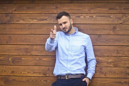 Portrait of a handsome man in a shirt on a wooden wall background. Businessman, boss in stylish clothes. Stock Photo for designの写真素材