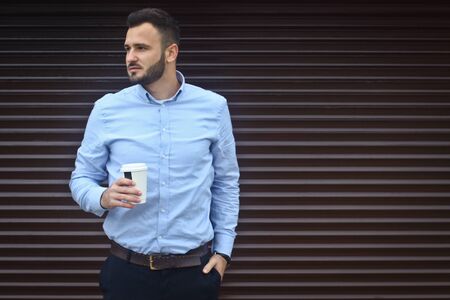 Portrait of a businessman, manager on a striped wall background. Bearded sexy man singing coffee, tea. Stock photosの写真素材