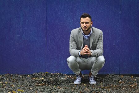 Fashionably dressed man against a blue wall. Cold winter, autumn weather. A warming guy. Stock Photo for designの写真素材